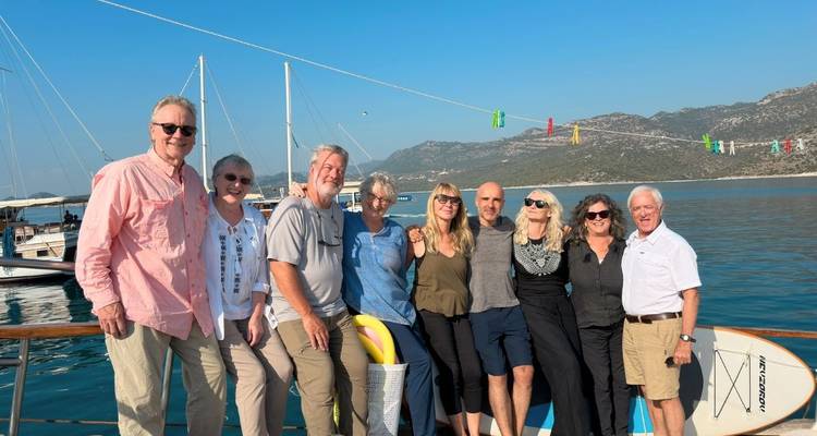Groupe de personnes posant pour une photo sur un bateau avec des montagnes en arrière-plan.