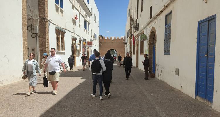 People walking down a street with historic white buildings.
