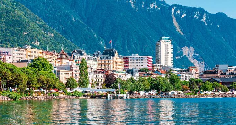 Paysage urbain coloré au bord d'un lac avec des montagnes en arrière-plan.