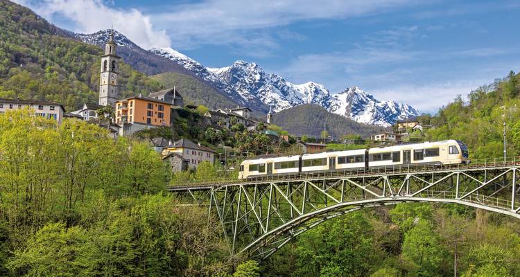 Train traversant un pont avec un décor de montagne en arrière-plan.