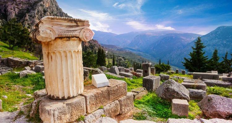 Altgriechische Ruinen vor einer bergigen Kulisse.