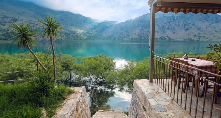 Vue sur le lac depuis une terrasse avec des montagnes en arrière-plan.