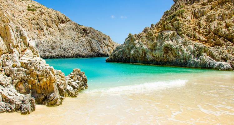 Crique de plage cristalline entourée de falaises rocheuses.