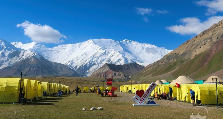 Campement de base avec des tentes dressées contre des montagnes enneigées.