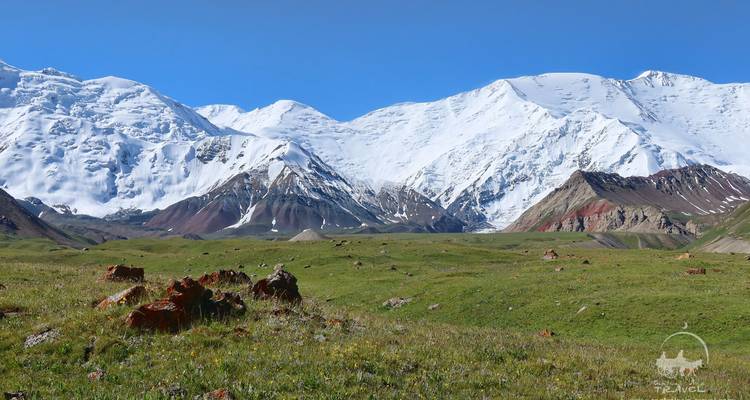 Collines ondulantes et montagnes majestueuses sous un ciel éclatant.