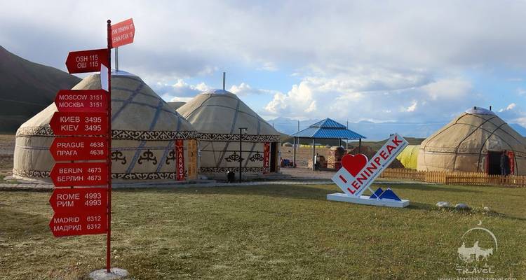 Yourtes et panneaux indiquant diverses villes dans un camping.