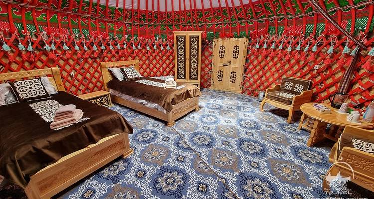 Vue intérieure d'une yourte avec des lits et une décoration traditionnelle.