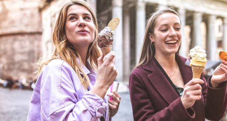 Deux femmes savourent des cornets de gelato devant les colonnes romaines antiques du Panthéon.