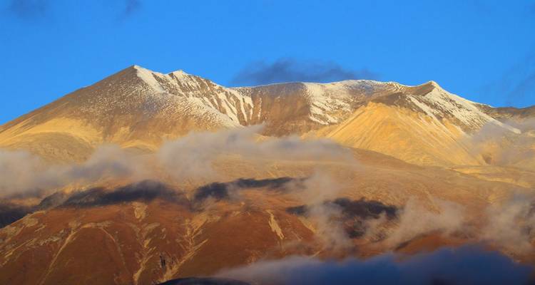 Paisaje montañoso con picos nevados bajo un cielo azul.