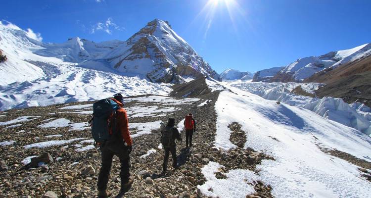 Excursionistas caminando por un sendero montañoso nevado.
