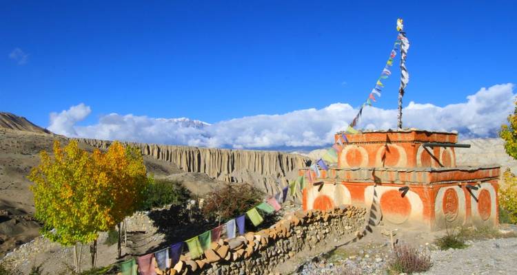 Estupa con banderas de oración y un telón de fondo montañoso.