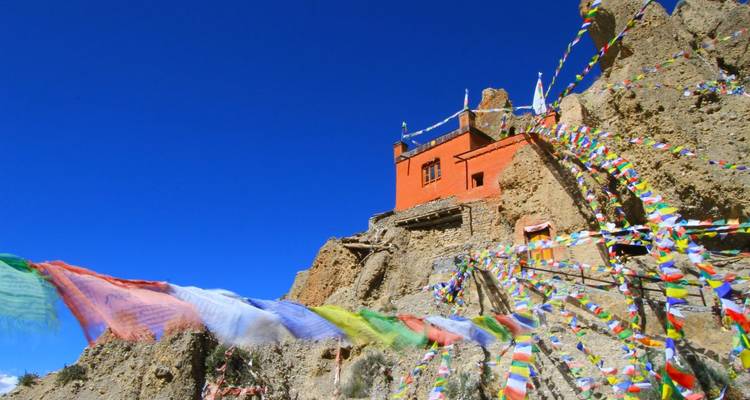 Banderas de oración coloridas y un edificio en la ladera de la montaña.