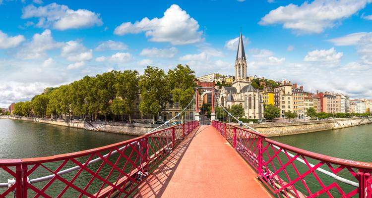 Voetgangersbrug Passerelle Saint-Georges in Lyon die zich uitstrekt over de Saône naar kleurrijke oude stadsgevels.