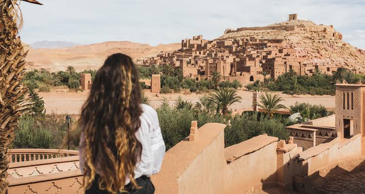 A person overlooking a historical town in a desert landscape.