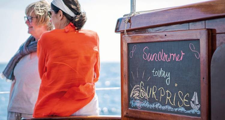 People on a boat, chalkboard sign reads 'Surprise'.