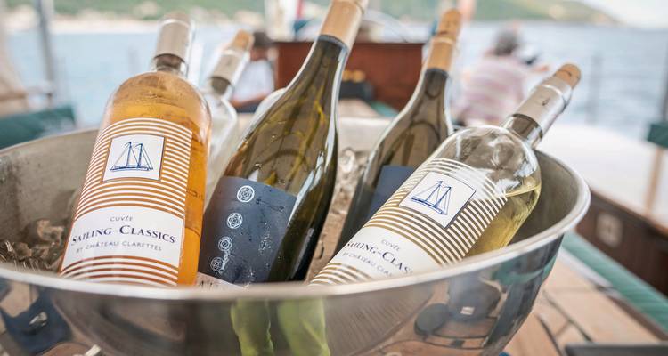 Bucket of assorted wine bottles on a table.