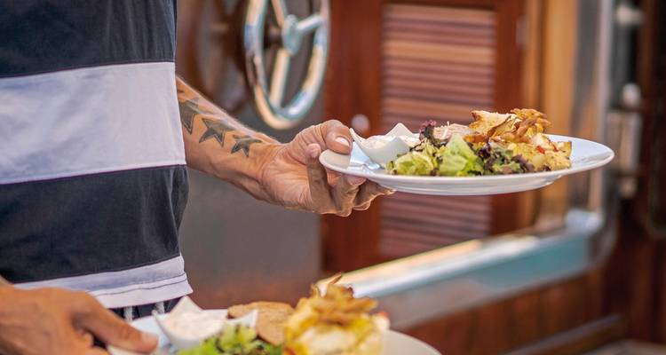 Person holding plates of food on a boat.