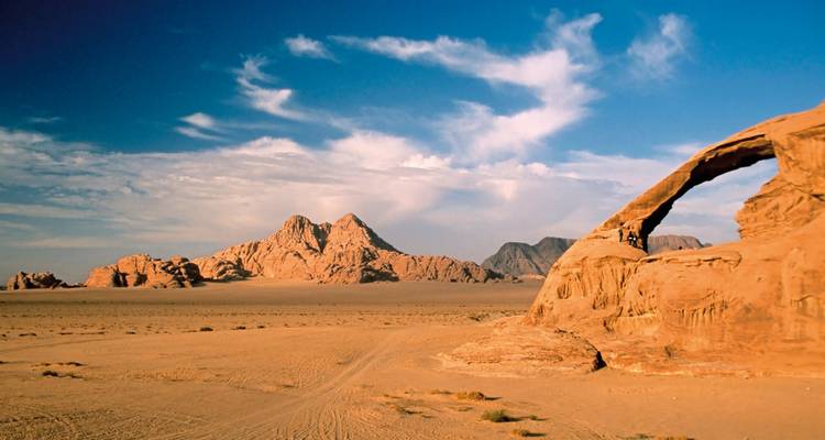 Desert landscape in Wadi Rum with rock formations under a blue sky.