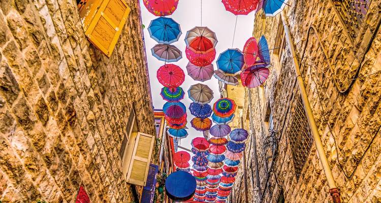 Colorful umbrellas hanging above a narrow street.