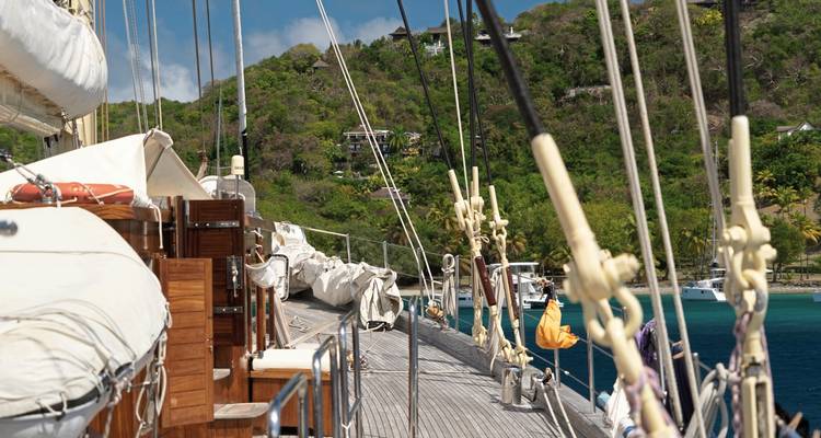 Pont de voilier avec vue sur le littoral et la mer.