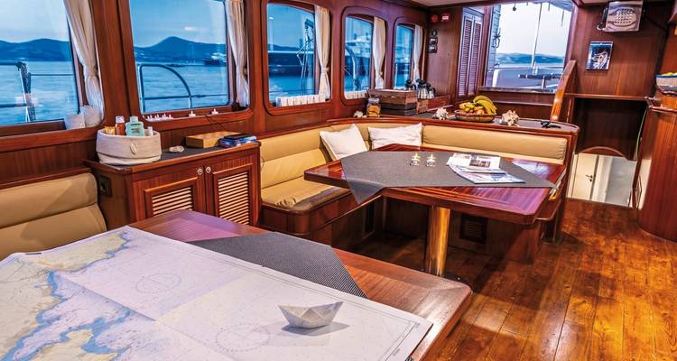 Intérieur d'un yacht avec coin salon, table et carte nautique.