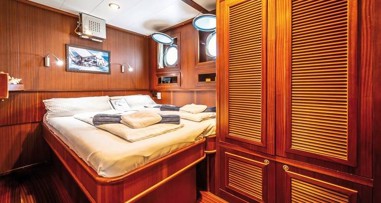Cabine de yacht confortable avec lit et mobilier en bois.