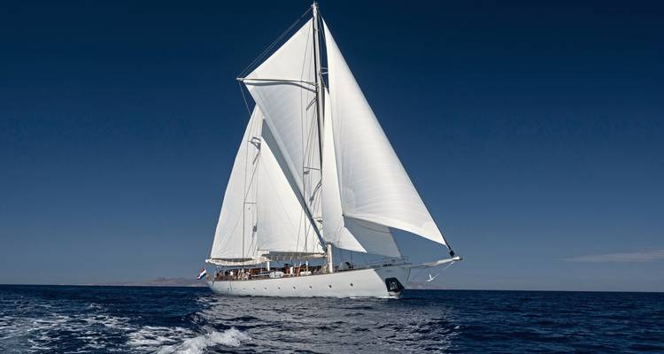 Voilier avec toutes voiles dehors contre un ciel et une mer d'un bleu profond.