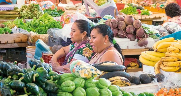 Market scene with vendors and a variety of fresh vegetables.