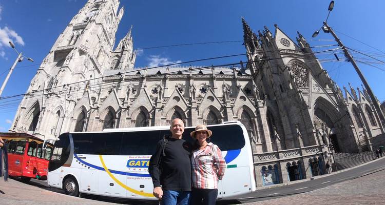Couple standing in front of a historic cathedral with a bus nearby.