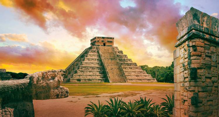 Ancient pyramid with dramatic sunset colors in the sky.