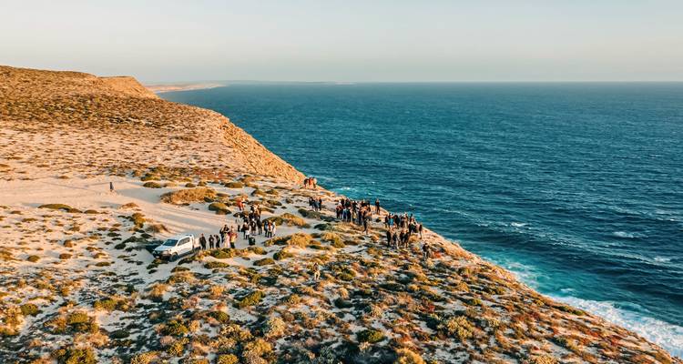 Groupe de personnes rassemblées sur une falaise au bord de l'océan.