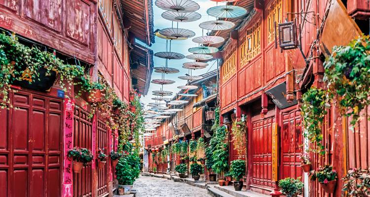 Rue colorée à Lijiang avec architecture traditionnelle et parapluies suspendus.