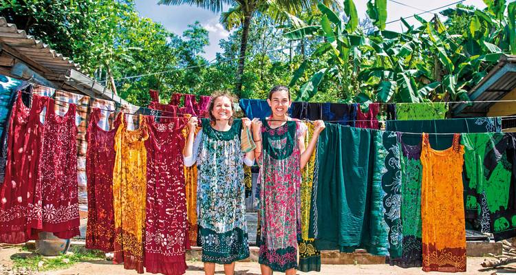 Des gens debout près de robes colorées suspendues à une corde.