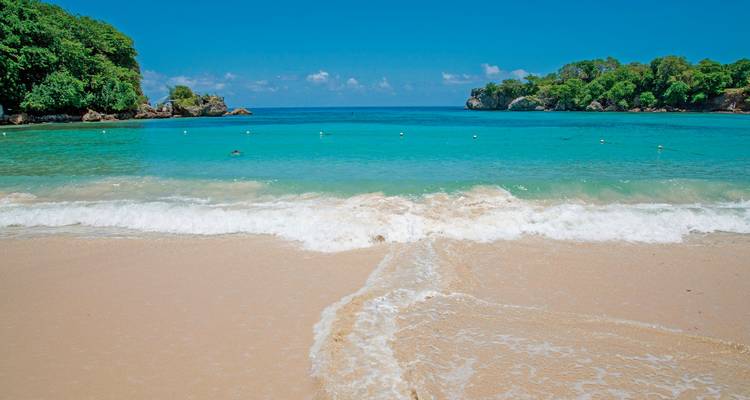 Une plage immaculée avec des eaux bleues claires et du sable blanc.