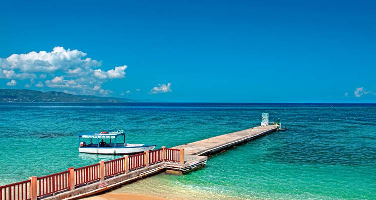 Un quai de bateau près d'eaux turquoise et d'un ciel dégagé.