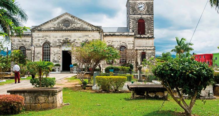 Une église historique avec un clocher entourée de verdure.