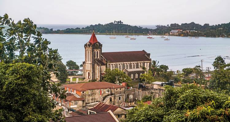 Une église avec un toit de tuiles rouges surplombant une ville côtière.