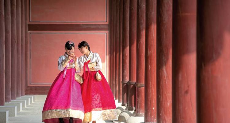 Twee mensen die traditionele Hanbok dragen in een Koreaanse paleisgang.