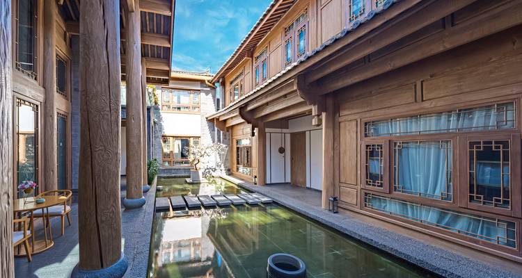 Cour traditionnelle avec architecture en bois et un petit bassin.