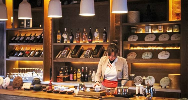 Barman préparant des boissons dans un bar avec un étalage organisé de produits.