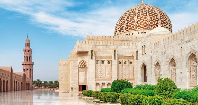 Une grande mosquée avec des jardins magnifiquement entretenus et un ciel bleu.