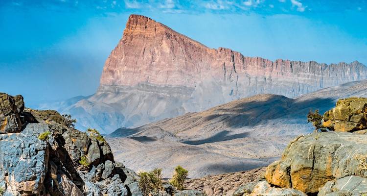 Un paysage rocheux avec un pic montagneux proéminent sous un ciel bleu dégagé.