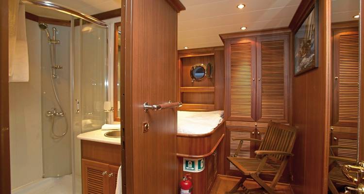 Cabine de yacht avec douche et mobilier en bois.