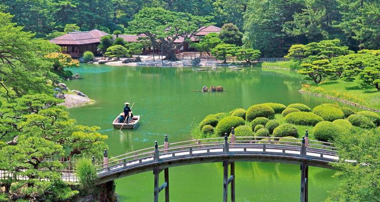 A traditional Japanese garden with a bridge and a boat.