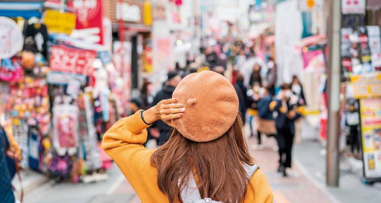 Überfüllte Einkaufsstraße mit einer Person, die der Kamera den Rücken zuwendet.