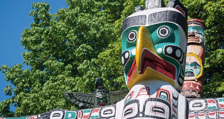 Vibrant and colorful totem pole against a backdrop of trees.