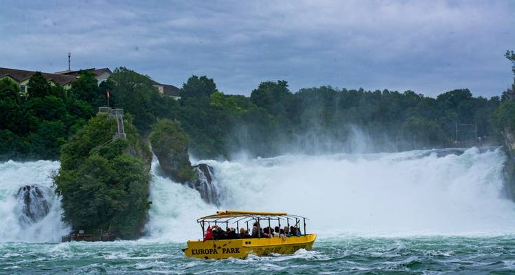 Boot nähert sich einem großen Wasserfall mit Passagieren an Bord.