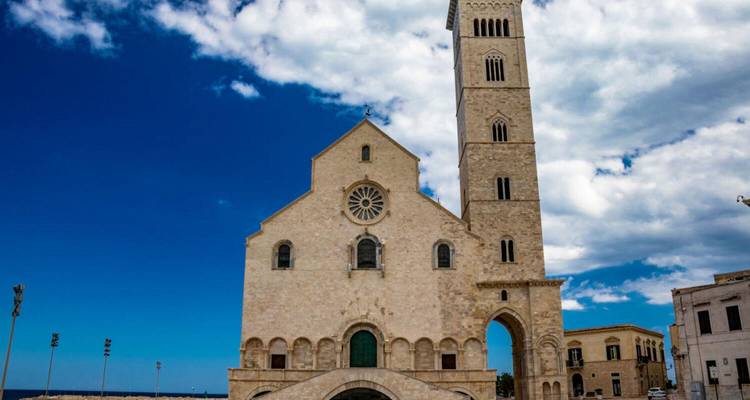 Cathédrale romane avec un clocher contre un ciel nuageux.