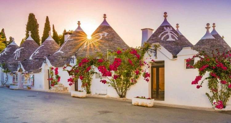 Rangée de maisons Trulli avec décorations florales au coucher du soleil.