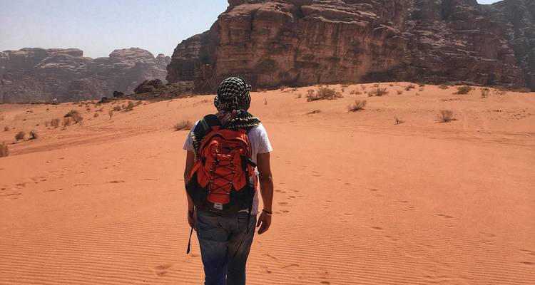 Personne marchant dans un paysage désertique avec des formations rocheuses.